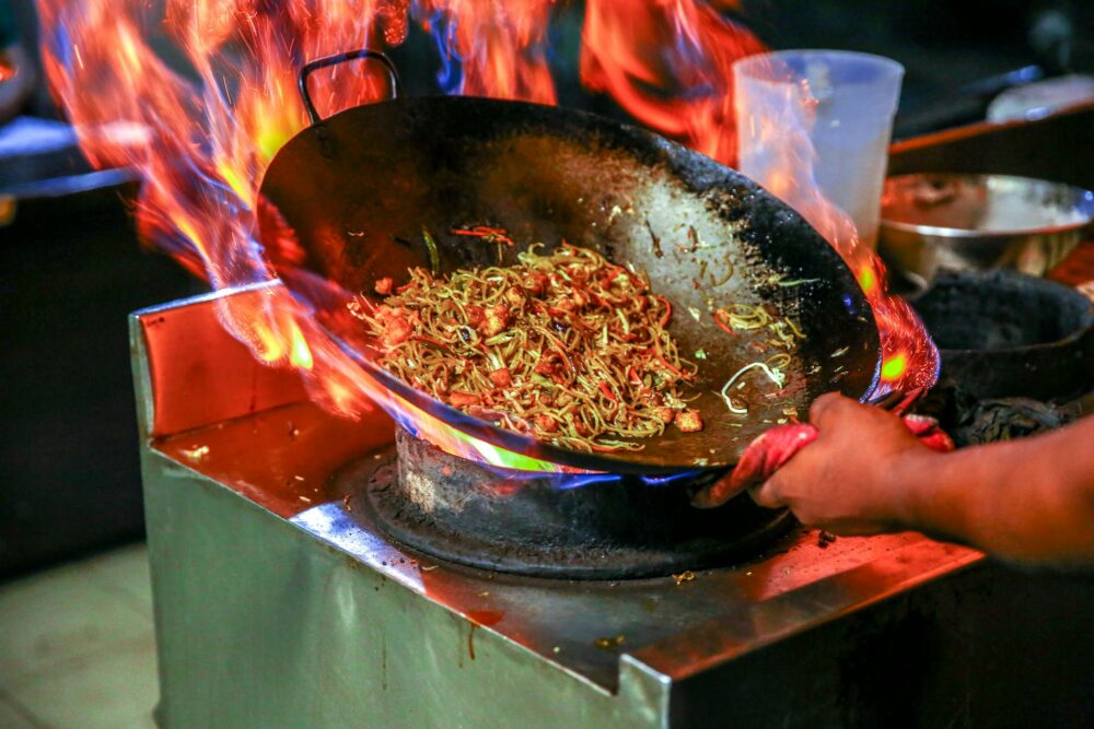 Cook preparing a dish in a wok