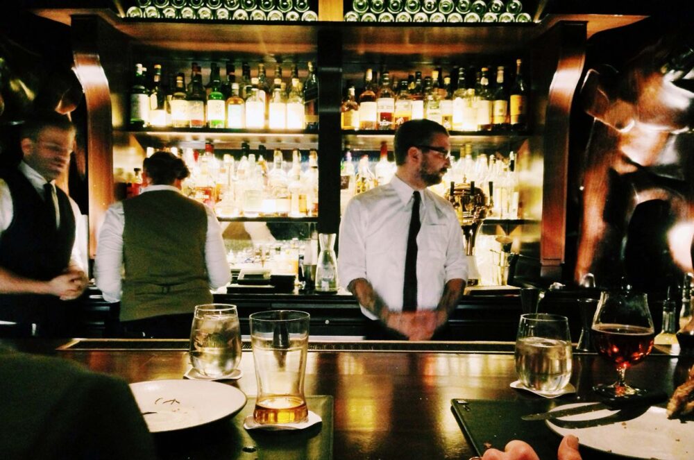 bartender standing beside the bar serving beer