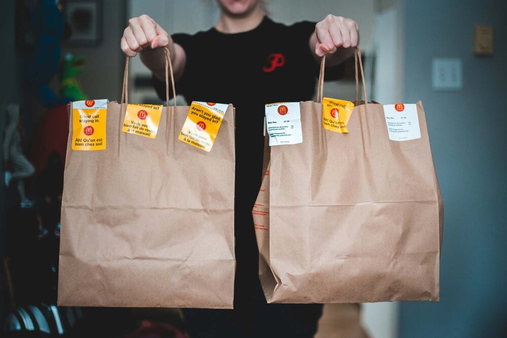 person holding white and brown tote bags