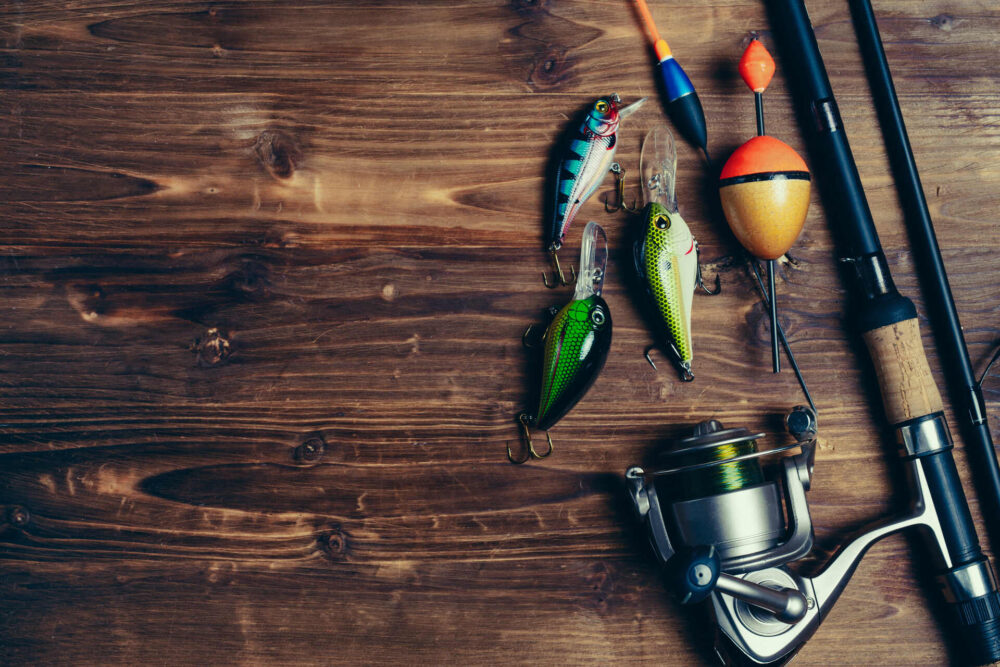  Fishing rod, reel, and various lures on a wooden table