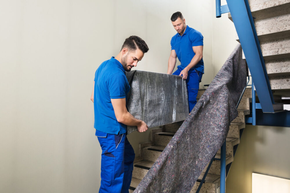 Long-distance movers carrying a large object down the stairs